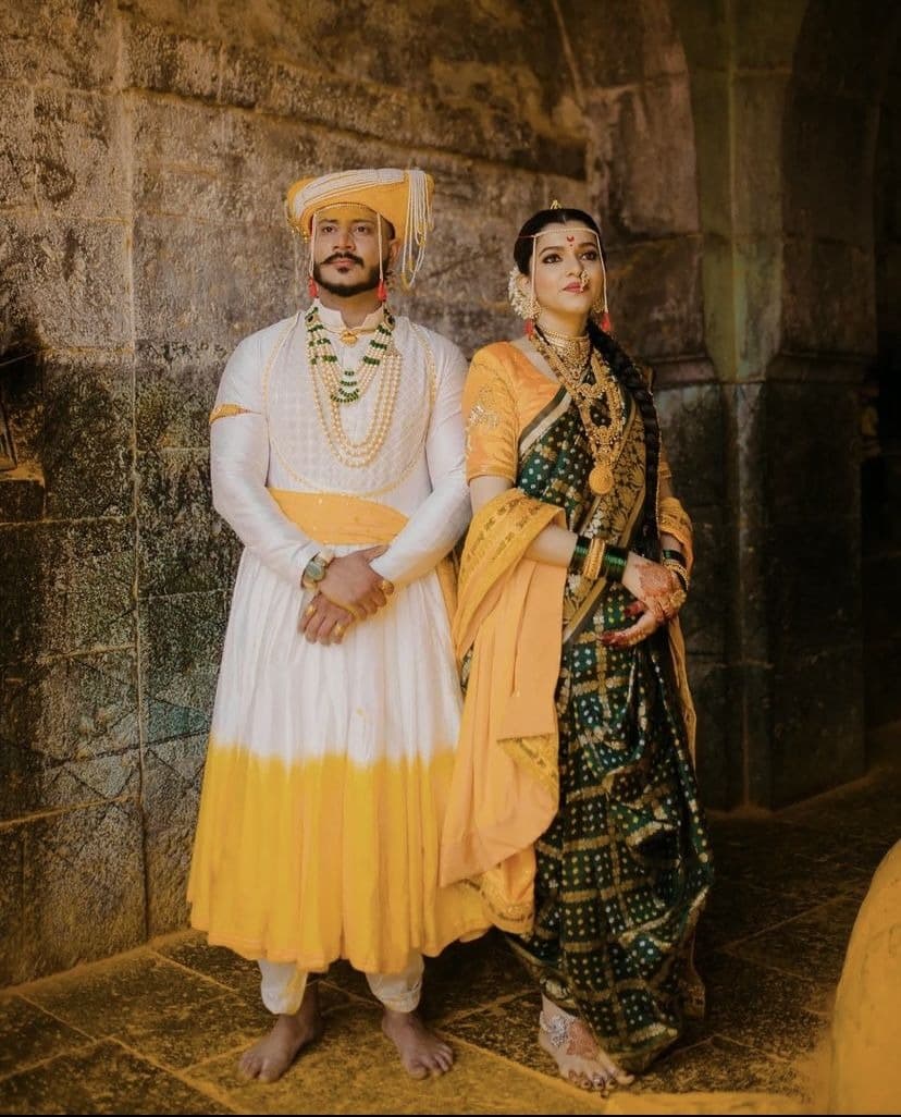 Couple in traditional Maharashtrian attire standing inside a stone fort