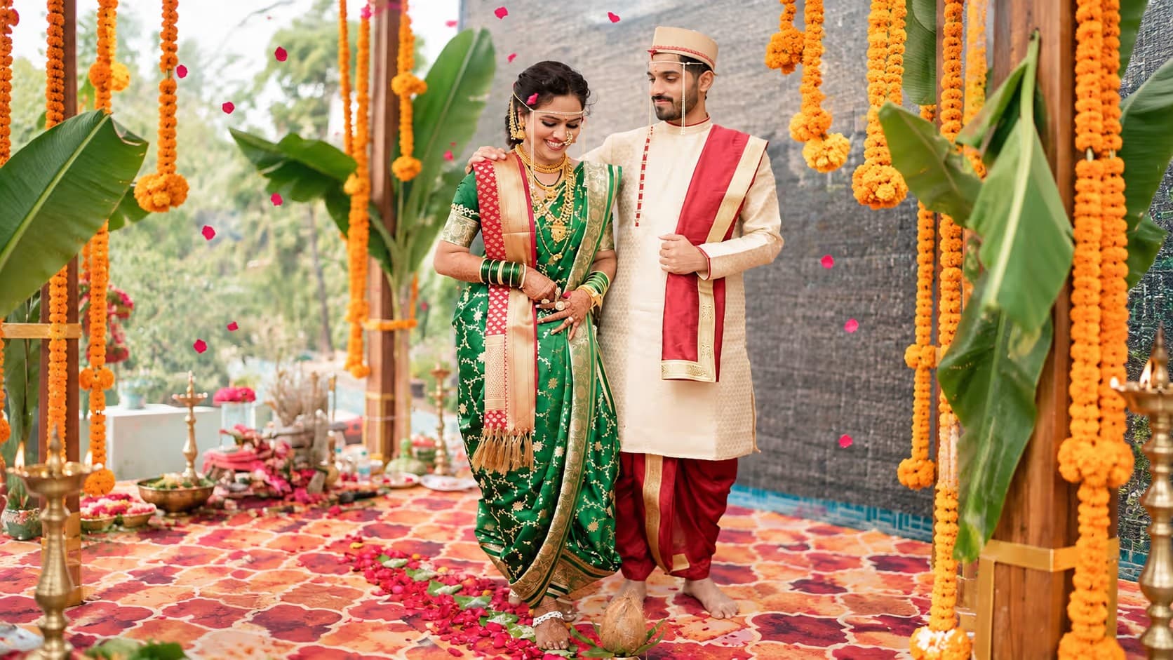 Bride and groom in traditional Maharashtrian wedding attire beneath marigold garlands